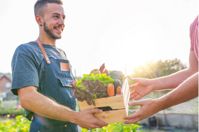 A vendor at the San Juan Island Farmers Market assists a patron with some produce.